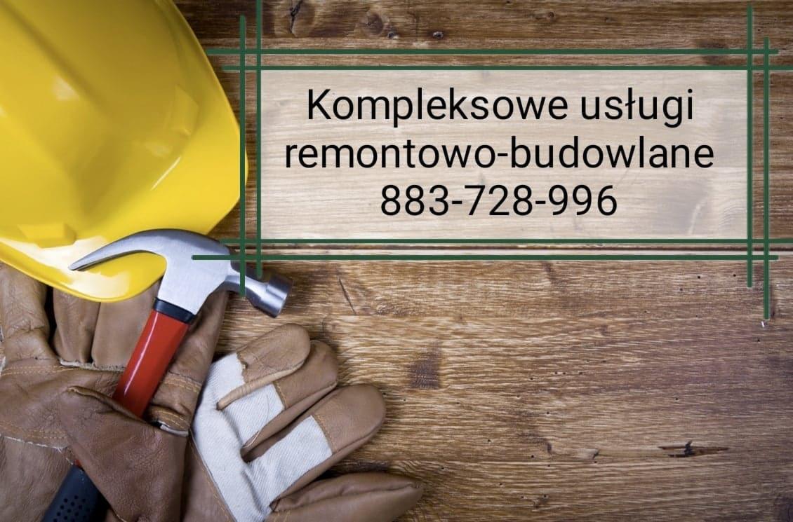 Żółty kask budowlany, rękawice robocze z białymi wzmocnieniami i młotek z czerwonym uchwytem na drewnianym tle z tekstem 'Kompleksowe usługi remontowo-budowlane 883-728-996' w zielonej ramce.