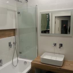 KTM-BUD JACEK LUBACZEWSKI - Nowoczesna łazienka z białą wanną, szklanym parawanem nawannowym, prostokątną umywalką nablatową i lustrem z odbiciem wnętrza