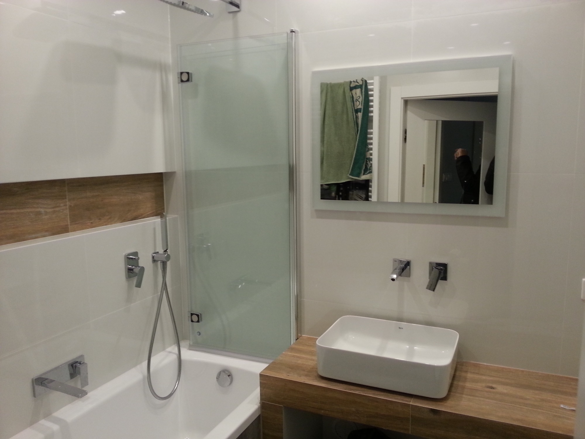 Nowoczesna łazienka z białą wanną, szklanym parawanem nawannowym, prostokątną umywalką nablatową i lustrem z odbiciem wnętrza