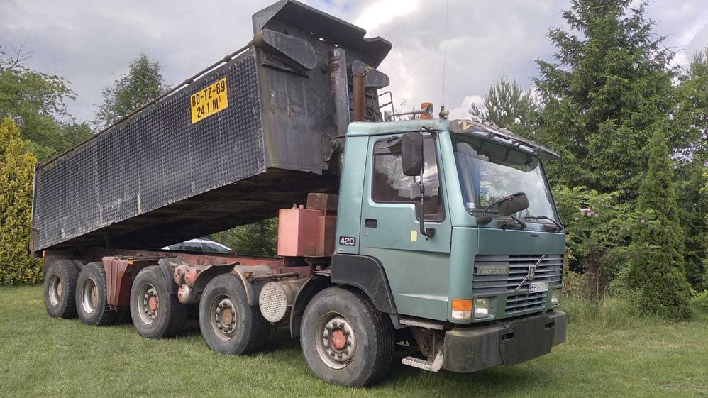 Ciężarówka wywrotka Volvo 420 z podniesioną skrzynią ładunkową na trawiastym terenie. Widoczna tablica z numerem rejestracyjnym i oznaczeniem pojemności 24,1 m3.