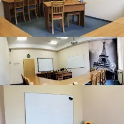 Sala lekcyjna z drewnianymi ławkami i krzesłami, tablicą suchościeralną, plakatem z napisem 'Market Leader' i tapetą z wieżą Eiffla, przygotowana do zajęć językowych.