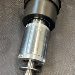 Enermetcnc - Precyzyjnie wykonane wrzeciono frezarki CNC z widocznymi śladami obróbki skrawaniem, umieszczone na ciemnym, teksturowanym tle.