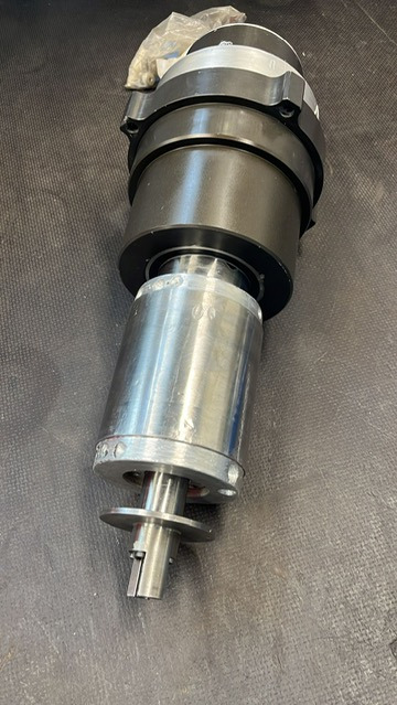 Precyzyjnie wykonane wrzeciono frezarki CNC z widocznymi śladami obróbki skrawaniem, umieszczone na ciemnym, teksturowanym tle.