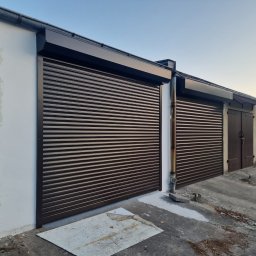 K-BRO sp. z o.o. - Zewnętrzne, brązowe osłony okienne typu rolowanego na garażach, widoczne ślady niedawnego malowania na posadzce i ścianie.