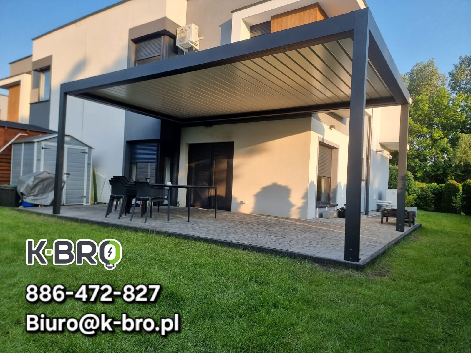 Nowoczesna pergola tarasowa z regulowanym zadaszeniem lamelowym, czarna konstrukcja, szare lamele, na tle domu z szarą stolarką okienną i zielonego trawnika.