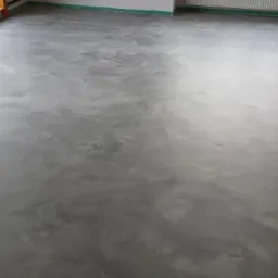 Szara, błyszcząca podłoga z efektem chmurkowania, zabezpieczona taśmą malarską przy ścianach i oknach.