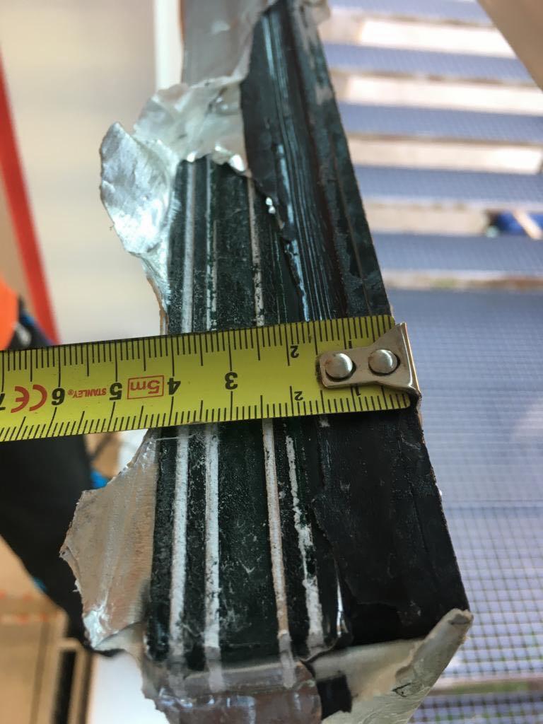 Pomiar szerokości ramy okiennej z uszkodzonym uszczelnieniem za pomocą miarki Stanley.