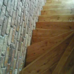 Drewniane schody z widoczną ścianą z cegły dekoracyjnej w Krakowie, ujęcie z dołu.