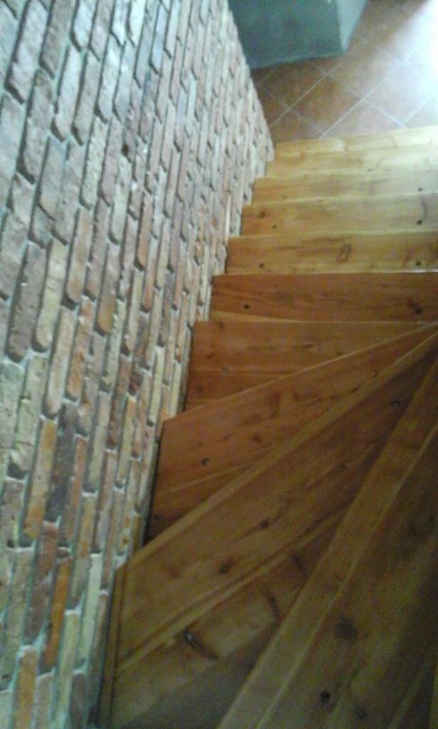 Drewniane schody z widoczną ścianą z cegły dekoracyjnej w Krakowie, ujęcie z dołu.