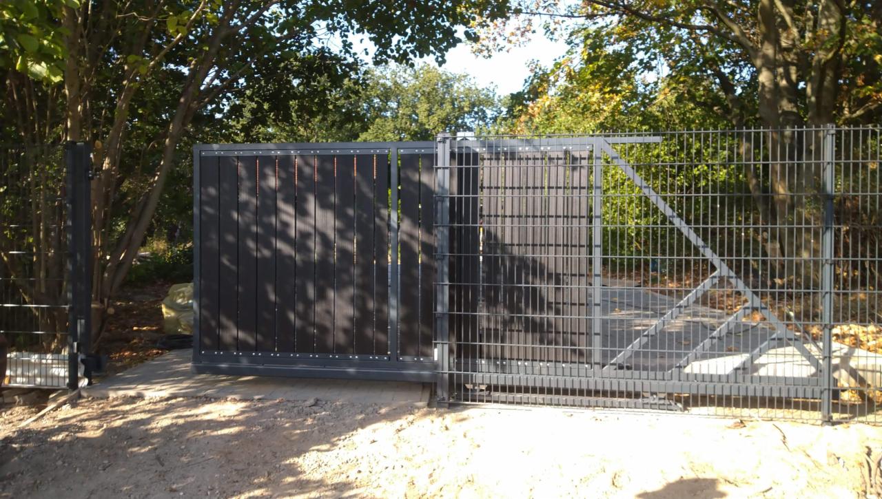 Nowoczesna brama wjazdowa z częściowo zabudowanym panelem z ciemnego drewna kompozytowego i metalową kratą, widoczna na tle drzew