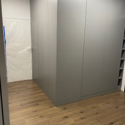 ANNA KUCNER - Szara szafa wnękowa z półkami, wykonana na wymiar, z drewnopodobną podłogą, drzwi zabezpieczone folią ochronną.