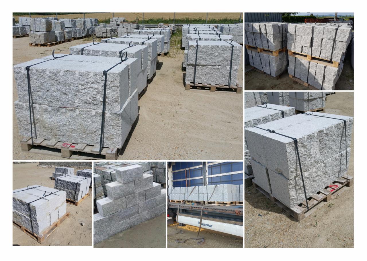 Skladowane na zewnątrz palety z szarą kostką, zabezpieczone czarną taśmą, w tle widoczny transport ciężarowy.