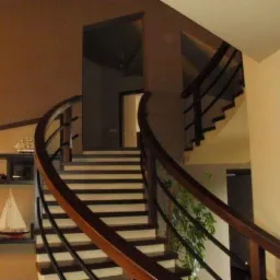 Klatka schodowa w domu z drewnianymi schodami i balustradą oraz półkami z modelami statków i samochodów.