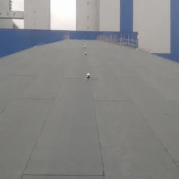 Skośny dach pokryty papą termozgrzewalną z widocznymi odpowietrznikami, na tle konstrukcji Elektrowni Opole.