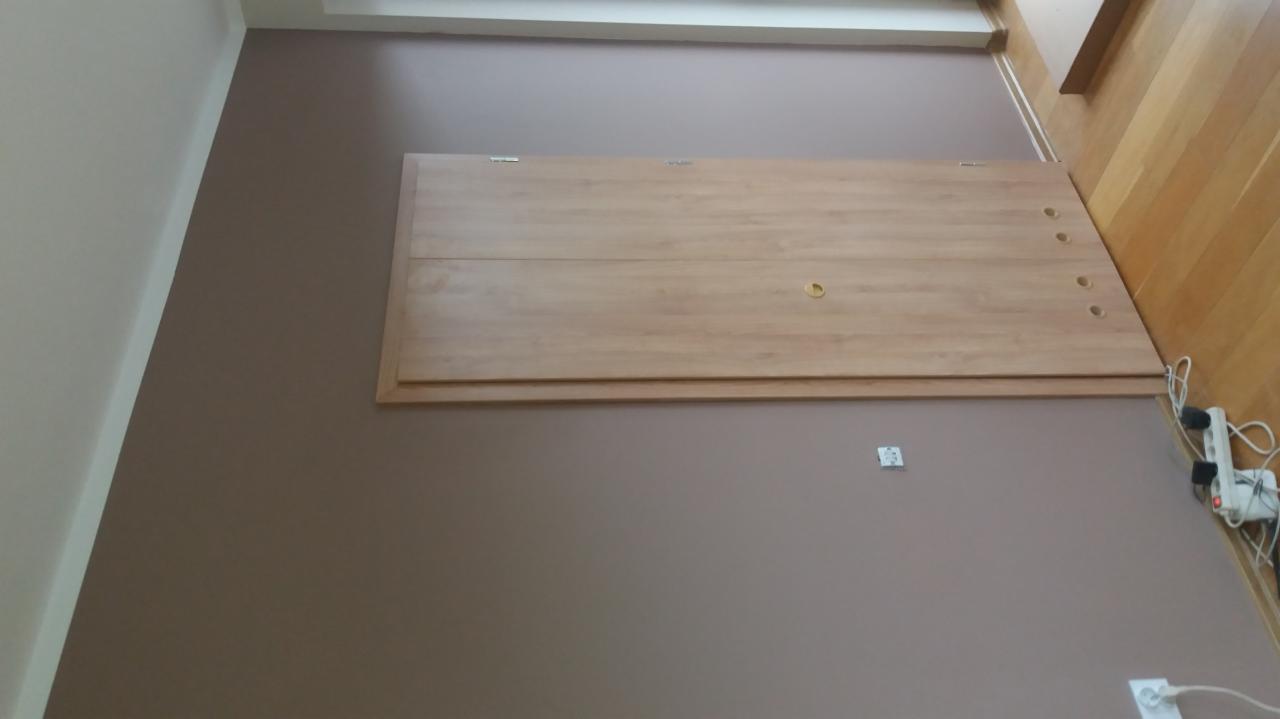 Świeżo pomalowana ściana w odcieniach brązu z zamontowaną drewnianą klapą rewizyjną i gniazdkami elektrycznymi w dolnej części ściany.