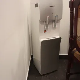 Dystrybutor wody Waterpia w Bielanach Wrocławskich, widoczny obok fragmentu krzesła w pomieszczeniu biurowym.