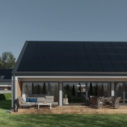 Dom Bez Kosztów - Nowoczesny dom z panelami słonecznymi na dachu i tarasem z meblami ogrodowymi, na trawniku dziecko gra w piłkę przy bramce.