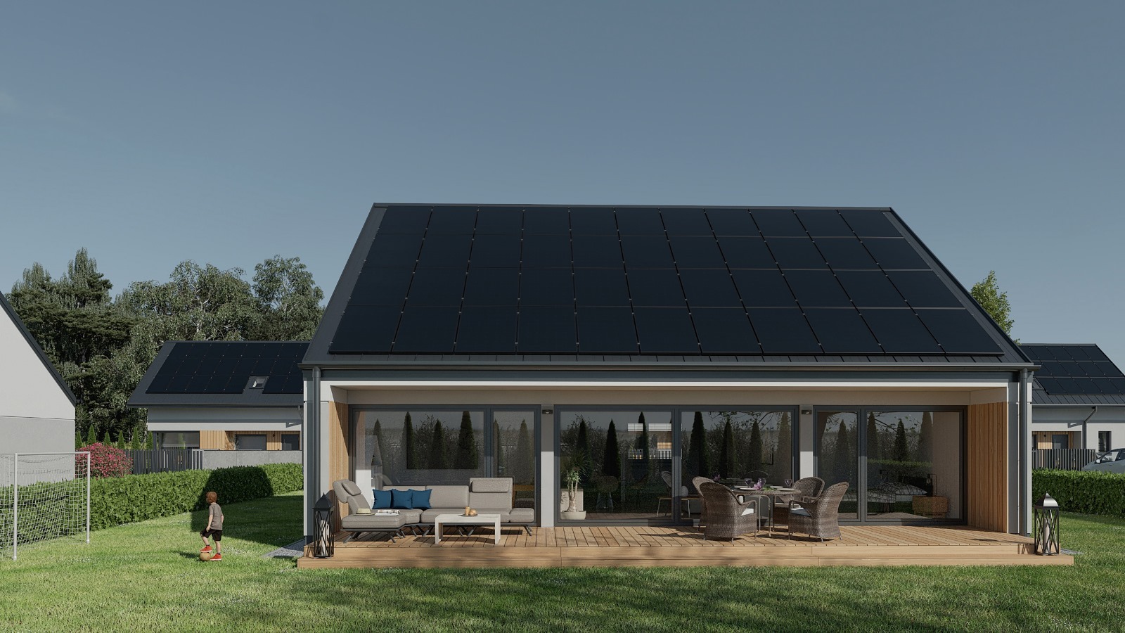 Nowoczesny dom z panelami słonecznymi na dachu i tarasem z meblami ogrodowymi, na trawniku dziecko gra w piłkę przy bramce.