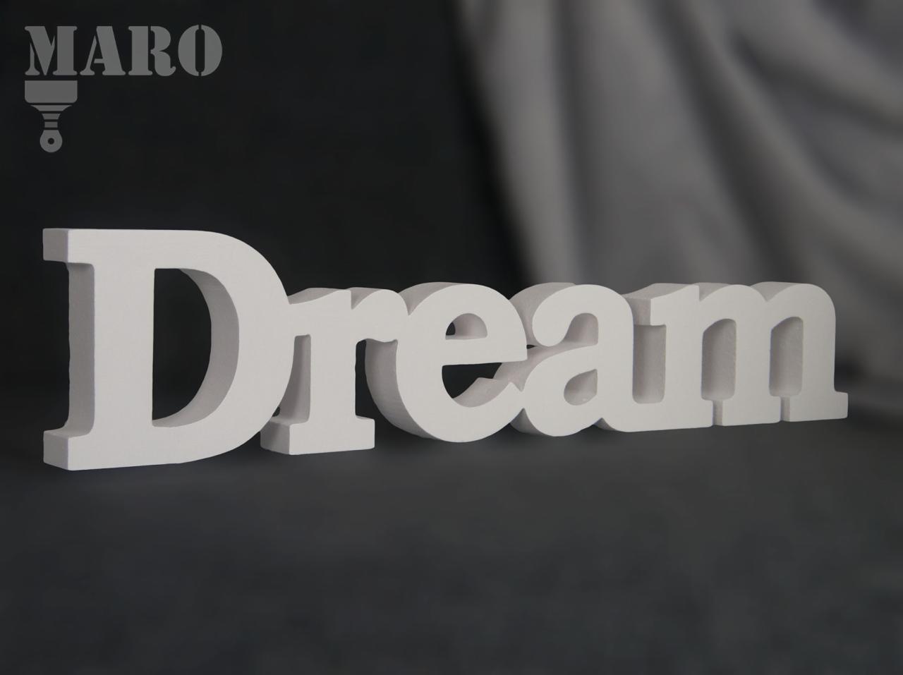 Biały, przestrzenny napis 'Dream' na ciemnoszarym tle, z logo firmy MARO w lewym górnym rogu.