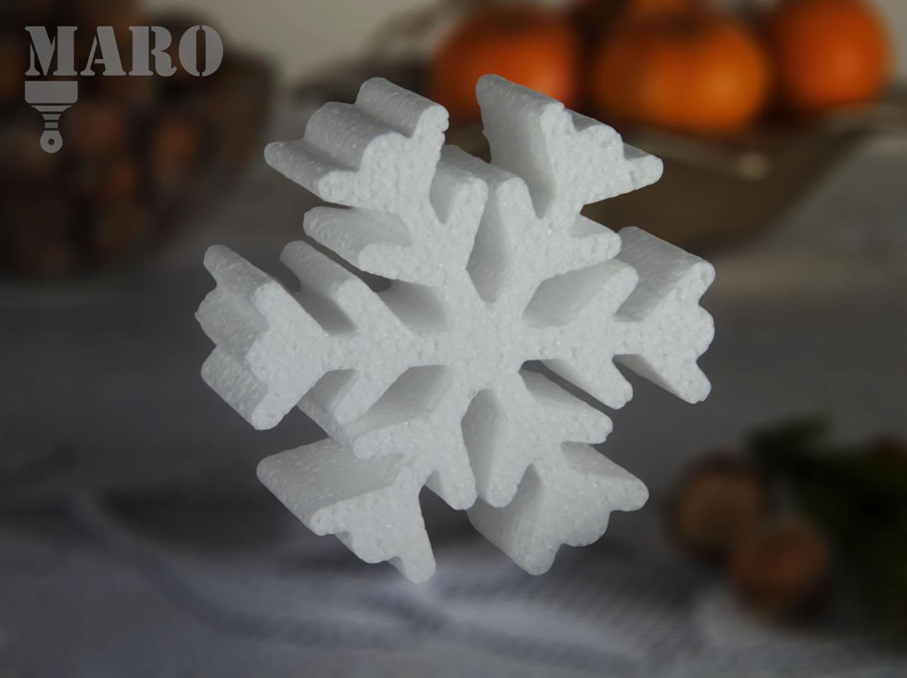 Biała, przestrzenna śnieżynka ze styropianu na rozmytym tle z owocami w koszyku i logiem firmy MARO w lewym górnym rogu.