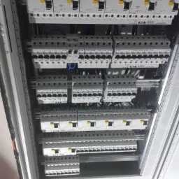 Rozdzielnica elektryczna z zamontowanymi bezpiecznikami firmy EATON, widok z góry, przewody elektryczne podłączone do poszczególnych zabezpieczeń.