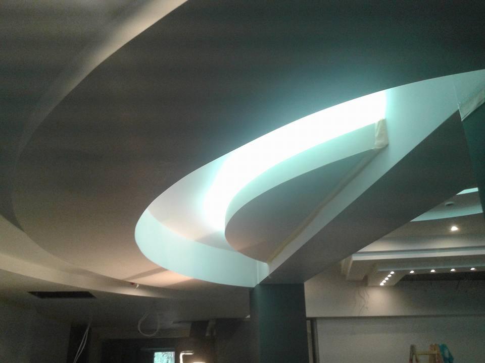 Nowoczesny sufit podwieszany z oświetleniem LED w kształcie łuku, widoczne niedoskonałości wykończenia i taśma malarska.