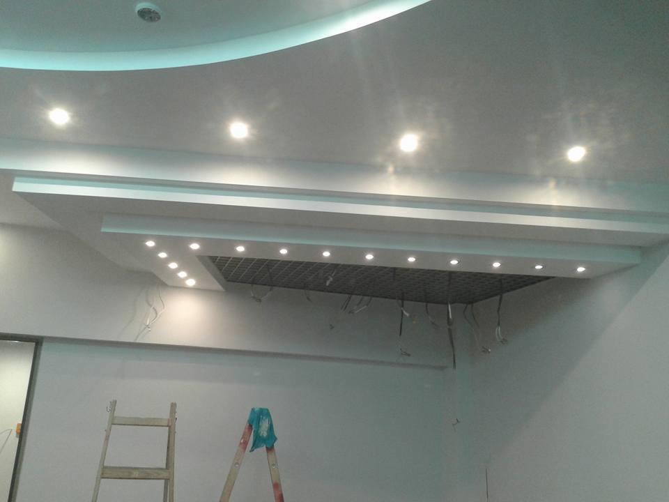 Wykończony sufit podwieszany z oświetleniem punktowym i kratką wentylacyjną, widoczne przewody elektryczne, drabina oparta o ścianę.