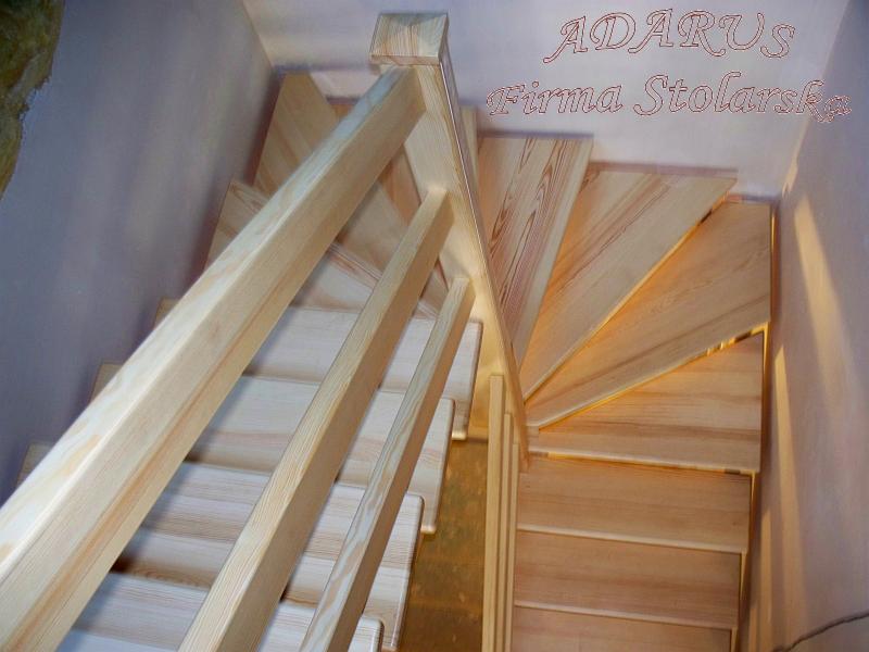 Jasne, drewniane schody kręcone z balustradą, widok z góry, w tle ściana z napisem 'ADARUS Firma Stolarska'.