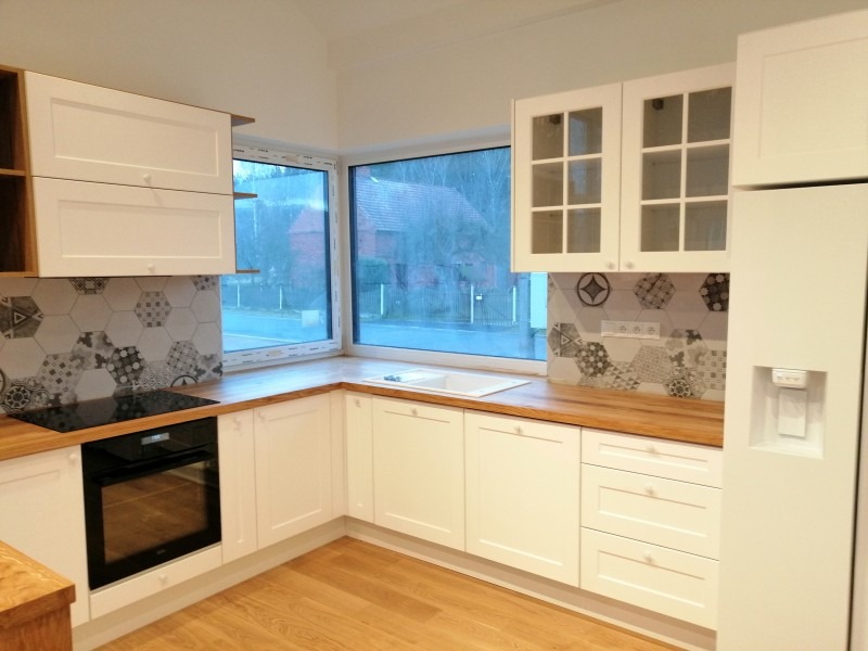 Jasna kuchnia z drewnianym blatem i heksagonalnymi płytkami w Złotoryi, widok na okno z zewnątrz.