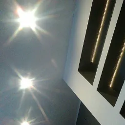 Sufit z trzema wbudowanymi lampami punktowymi i dwoma podłużnymi wnękami z oświetleniem LED, widok pod kątem.