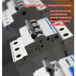 Tablica rozdzielcza z wyłącznikami automatycznymi marki Hager, z widocznym tekstem reklamowym firmy 'Marek Sawoniuk' oferującej instalacje elektryczne, alarmowe, monitoring i odgromowe.