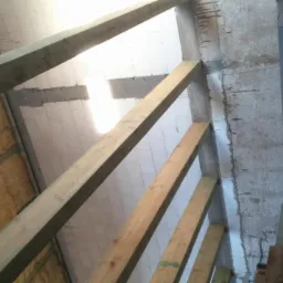 Wnętrze domu w trakcie budowy: ocieplenie ścian wełną mineralną, drewniane belki konstrukcyjne i surowe ściany z betonu komórkowego.