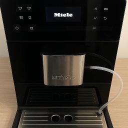 OlsTech Group Serwis Rubinkowo - Czarny ekspres do kawy Miele z podłączonym pojemnikiem na mleko i wyświetlaczem. Widoczny numer telefonu na dole zdjęcia.