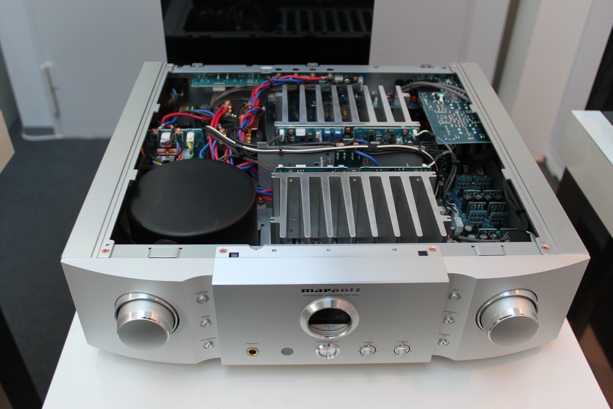 Otwarty wzmacniacz Marantz PM-10S1 z widocznymi elementami wewnętrznymi: radiatory, kondensatory i płytki drukowane. Srebrna obudowa, czarny transformator toroidalny.