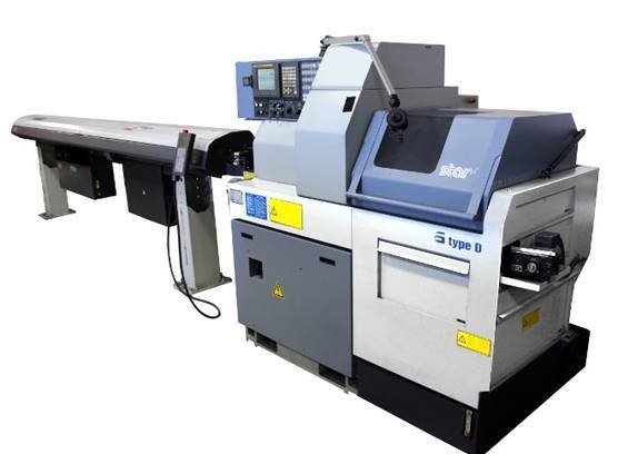 Precyzyjna, nowoczesna tokarka CNC typu D z podajnikiem prętów, oświetlona z góry, z widocznym panelem sterowania.
