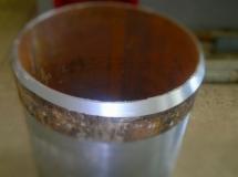 Wnętrze metalowej rury z wyraźnym śladem obróbki na krawędzi, widoczne drobne nierówności i przebarwienia. Obróbka wykonana z dużą precyzją.