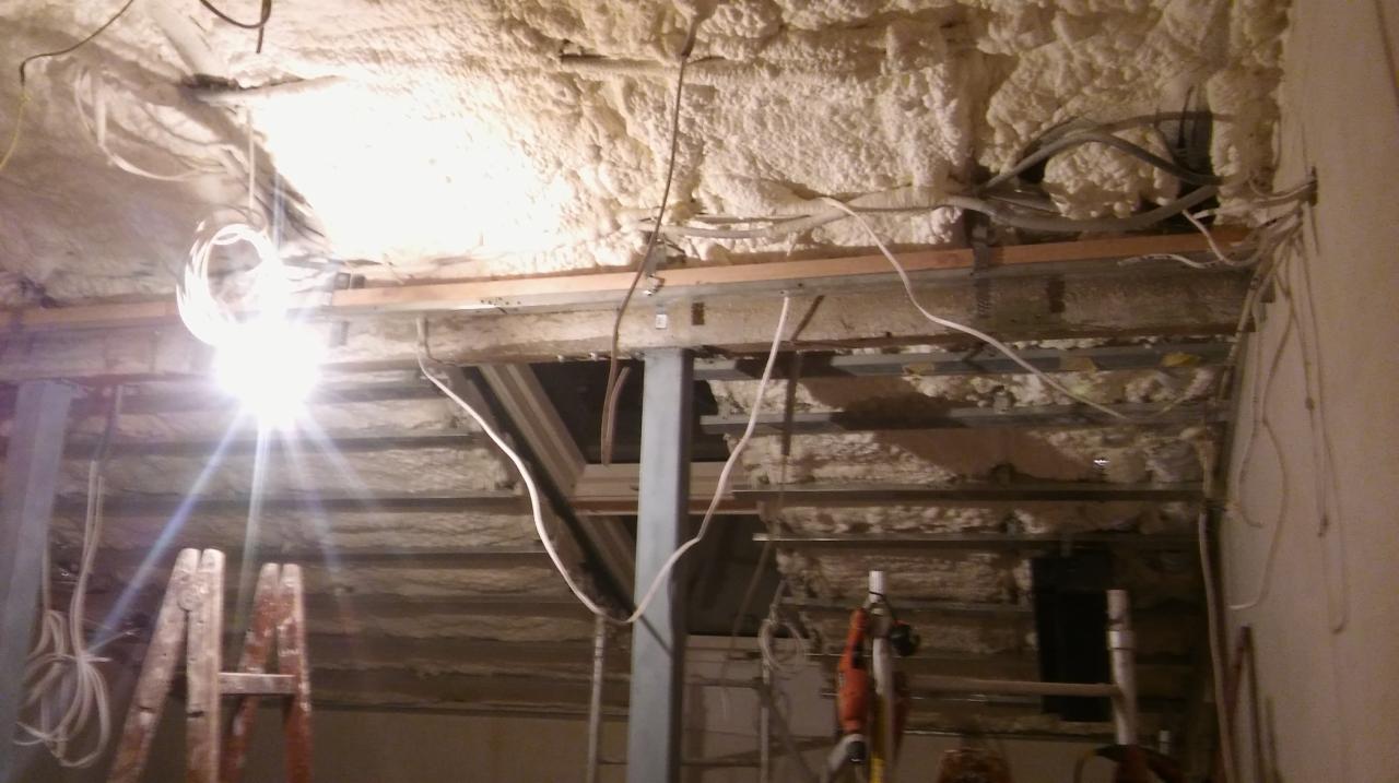 Poddasze w trakcie izolacji pianą PUR, widoczne metalowe profile konstrukcyjne, przewody elektryczne i drewniana drabina.