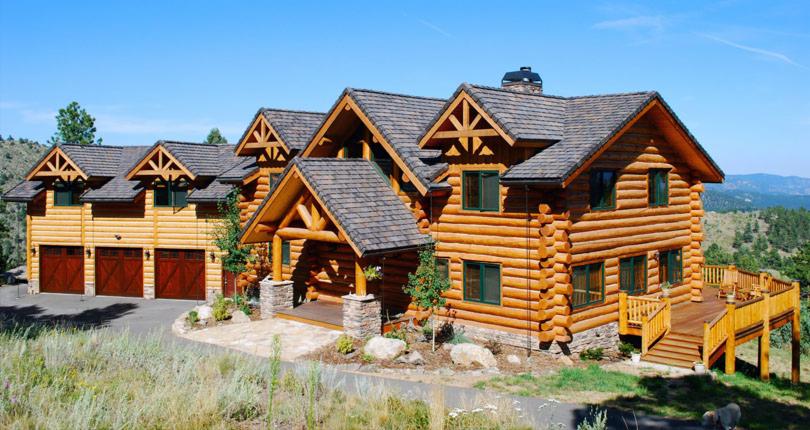 Dom z bali z drewnianą konstrukcją dachu, brązowymi oknami i garażem na trzy samochody, na tle zielonych wzgórz i błękitnego nieba.