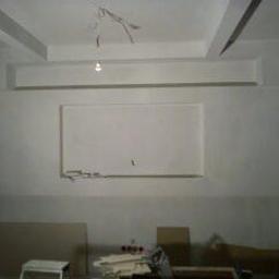 Primo-Rem - Wnętrze w trakcie przygotowania do prac wykończeniowych: surowe ściany z widocznymi elementami instalacji elektrycznej, częściowo zabezpieczone podłoże, widoczne narzędzia i materiały budowlane.