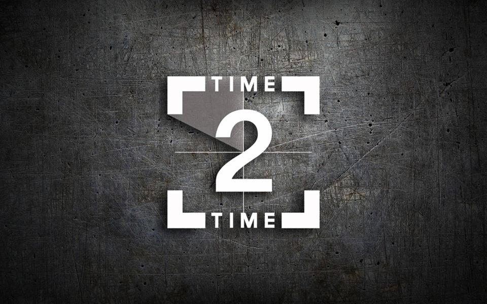 Grafika z napisem 'Time 2 Time' w białych, geometrycznych literach i cyfrach na tle ciemnej, metalicznej powierzchni z widocznymi zarysowaniami.