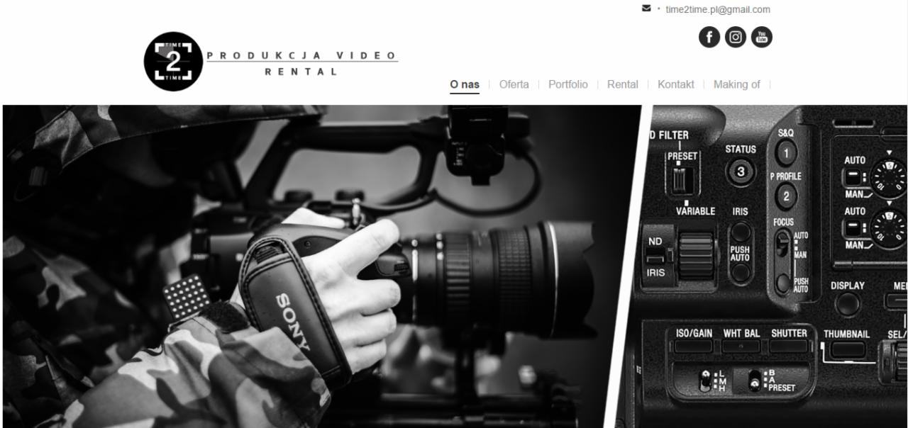 Czarno-białe zbliżenie na kamerzystę trzymającego profesjonalną kamerę Sony, widoczne ustawienia i przyciski na korpusie kamery oraz fragment kamuflażu na ubraniu operatora.