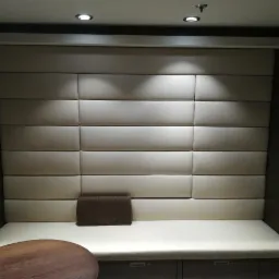 Narożnik tapicerowany panelami w odcieniach beżu, z brązową poduszką, wykonany na wymiar w Rychtalu. Widoczny fragment okrągłego stołu z ciemnego drewna.