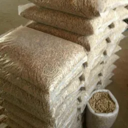 Stos worków z pelletem drzewnym, ułożonych jeden na drugim, z dodatkowym workiem otwartym obok.