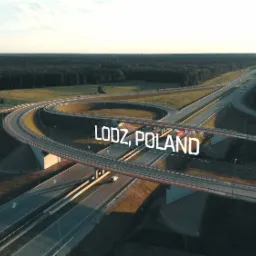 Panorama węzła drogowego w Łodzi z lotu ptaka, z widocznymi wiaduktami, drogami i otaczającym lasem.