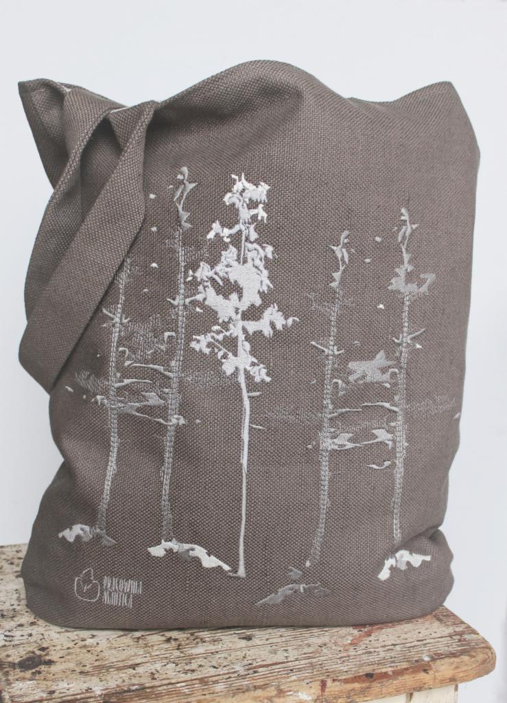Szara lniana torba na ramię z białym haftem przedstawiającym stylizowane drzewa iglaste.
