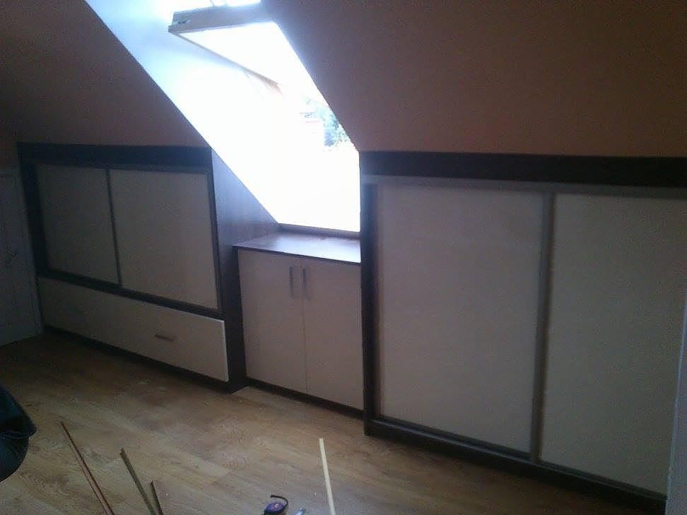 Szafa na wymiar z przesuwnymi drzwiami w zabudowie pod skosem poddasza, widoczne narzędzia na podłodze.