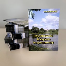 Golden Cat Studio - Stos wydrukowanych książek z okładką przedstawiającą krajobraz, obok pojedynczy egzemplarz z tytułem 'Myszkowski leksykon krajoznawczy'.
