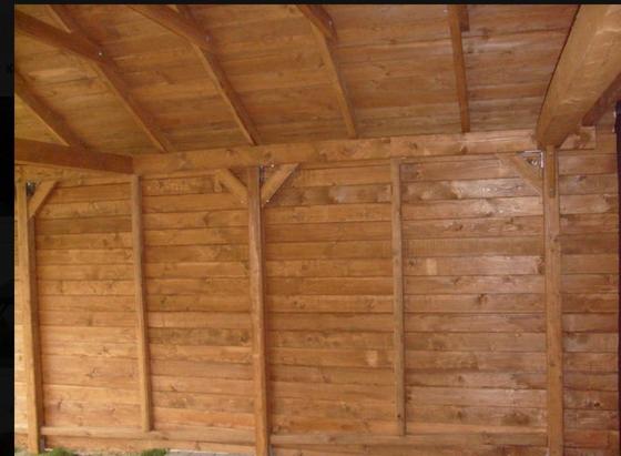 Drewniana konstrukcja z dachem, widoczne poziome deski i wsporniki, jasne drewno, budowa w toku.