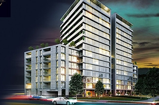 Nowoczesny apartamentowiec z jasną elewacją i licznymi balkonami, widoczny z perspektywy ulicy z przejeżdżającymi samochodami i zielenią w tle.