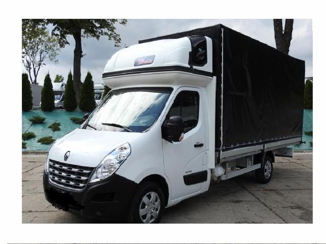 Biały Renault Master z plandeką na parkingu, widoczne drzewa i krzewy w tle.